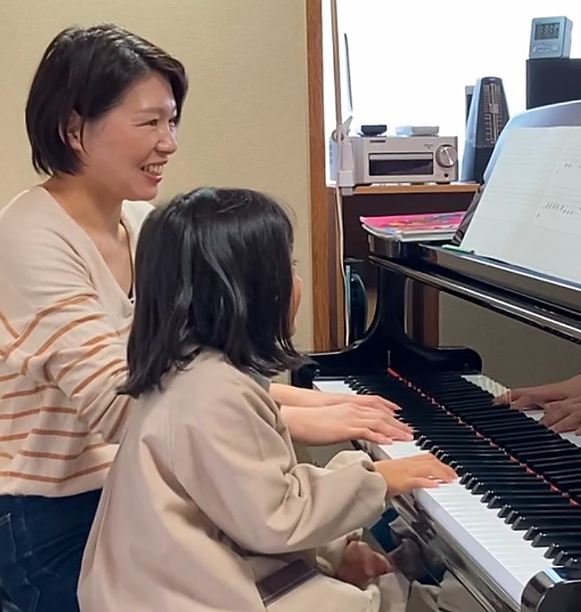 講師と一緒にグランドピアノを弾く生徒